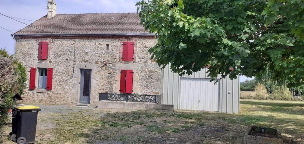 ein altes Steinhaus mit roten Rollläden und einer Garage in der Unterkunft Maison pittoresque et cozy in Bonnat