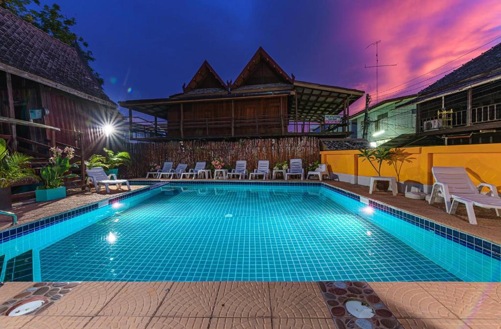 - une piscine en face d'une maison la nuit dans l'établissement MANDARIN LODGE by victor, à Hua Hin