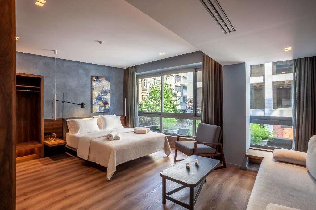 um quarto com uma cama, um sofá e janelas em Katouni25 Luxury Suites em Tessalônica