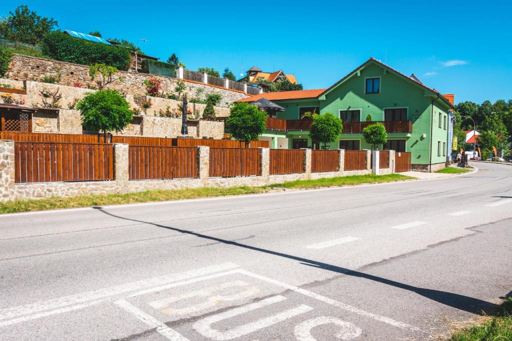 an empty street with a green house and a fence at Penzion Rechle in Český Krumlov