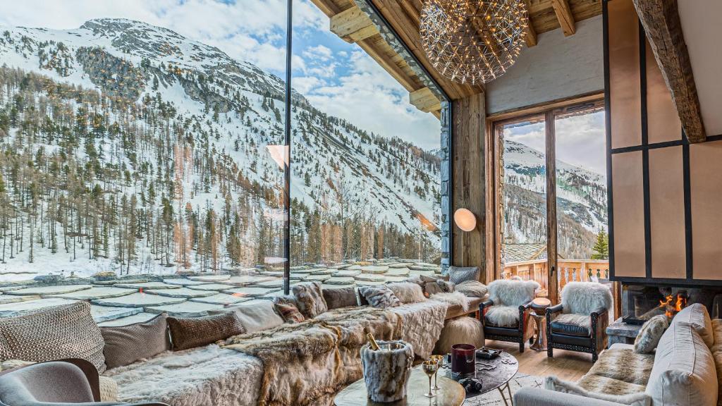 Cette chambre dispose de canapés et d'une grande fenêtre avec des montagnes enneigées. dans l'établissement Chalet Orca, Val d'Isère - 14 pers - 420m2, à Val dʼIsère