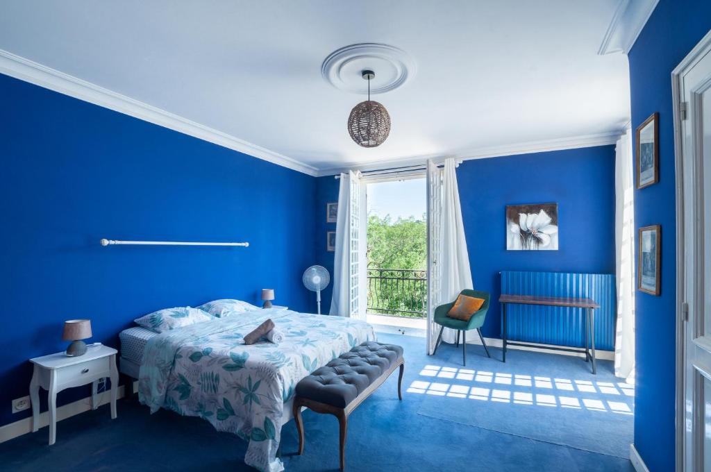 a blue bedroom with a bed and a chair at Au Bonheur Caché in Vianne