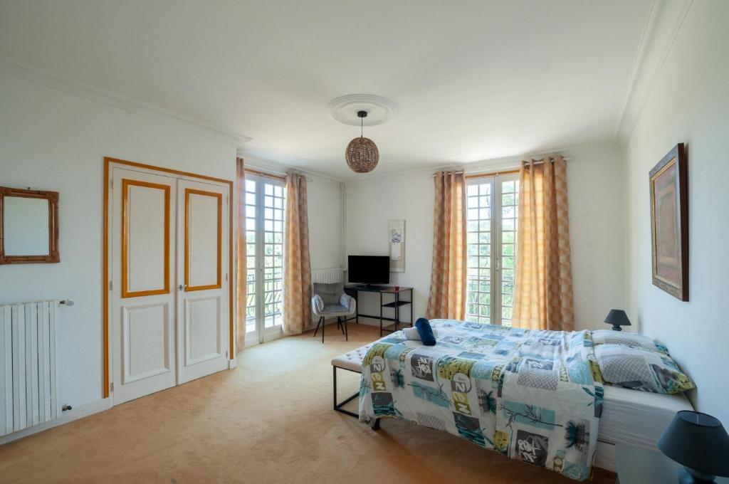 a bedroom with a bed and a desk and windows at Au Bonheur Caché in Vianne