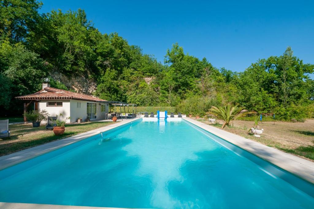 a large swimming pool with blue water in a yard at Au Bonheur Caché in Vianne