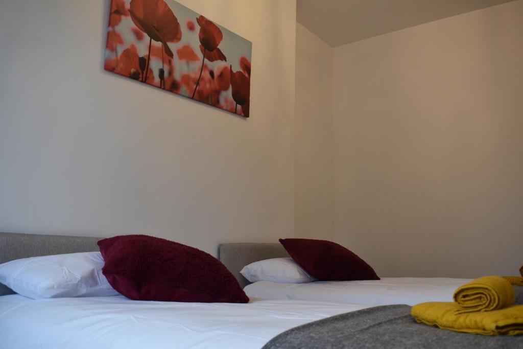 a bedroom with two beds with red and white pillows at Camri Room in Denbigh