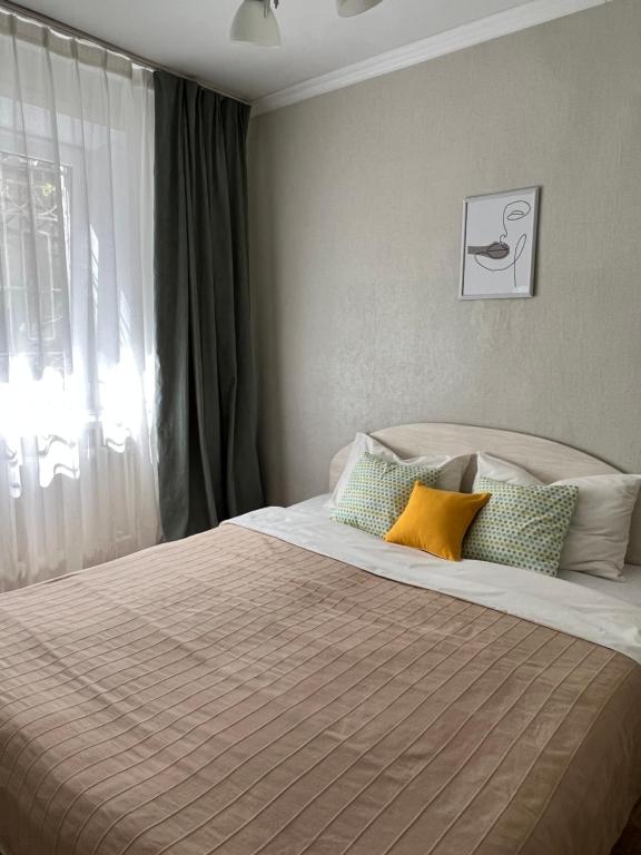 um quarto com uma cama com almofadas e uma janela em 2х комнатная квартира в центре города Уральска em Oral