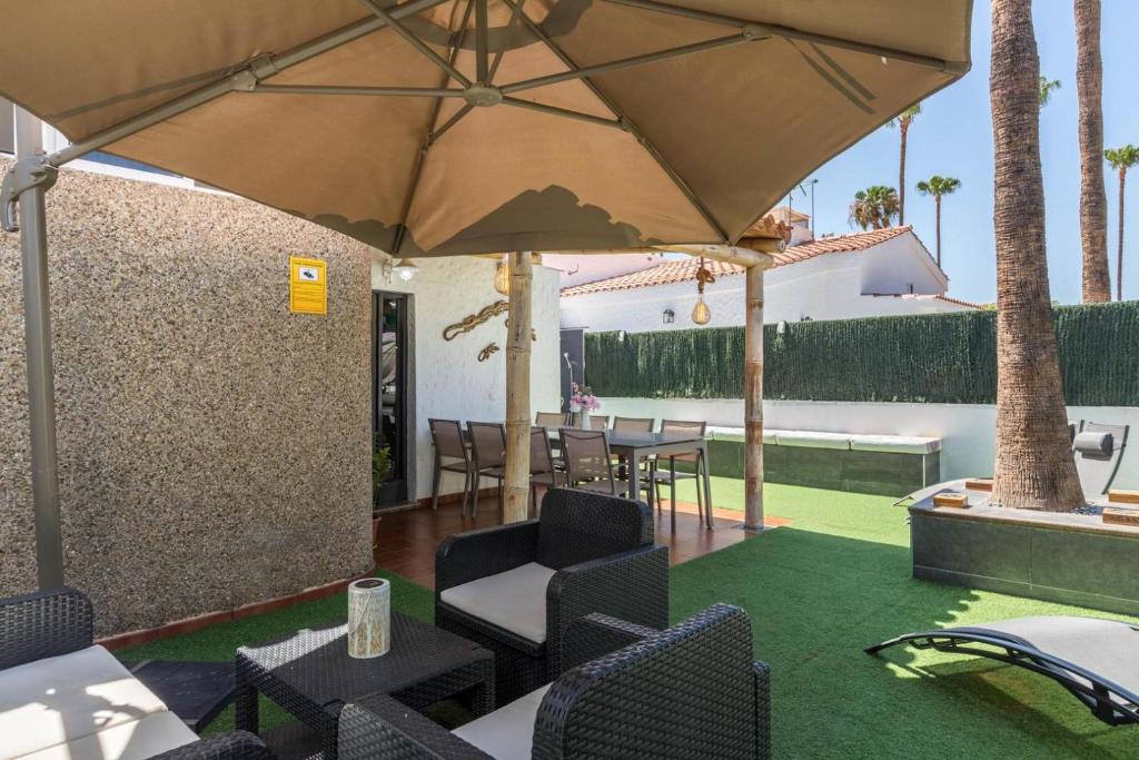 een terras met een tafel, stoelen en een parasol bij Ca Martina Sonora Golf in Maspalomas
