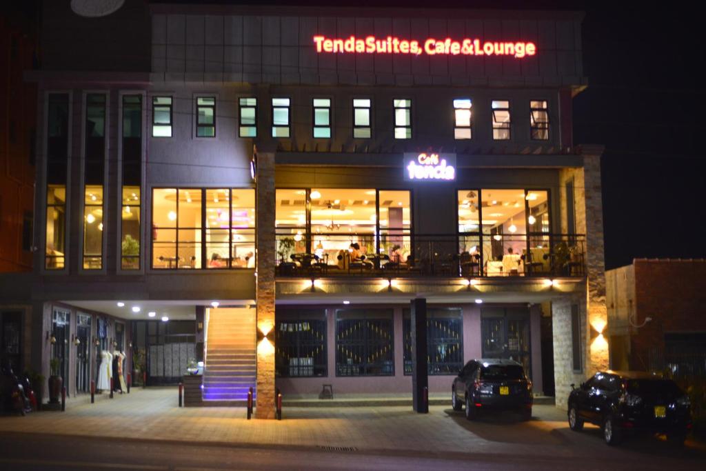 a building with a sign on the front of it at night at Tenda Suites and Restaurant in Entebbe