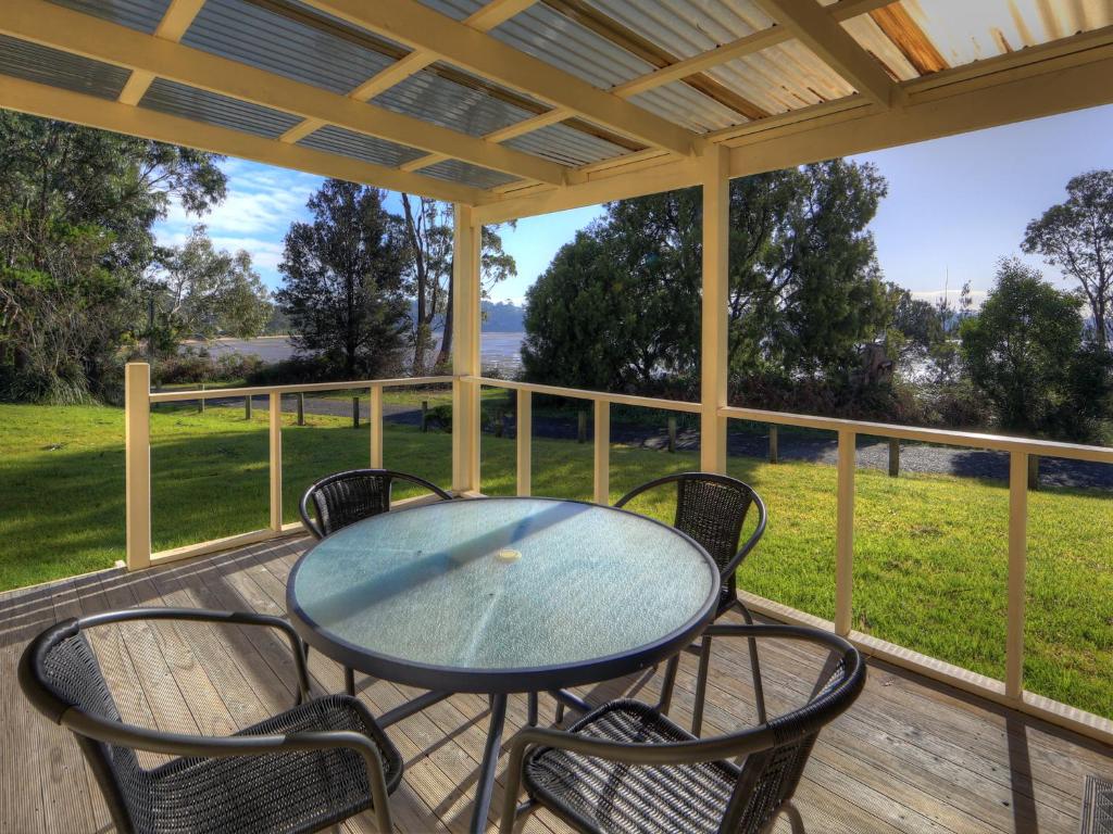 a table and chairs on a porch with a view of a field at Beauty Point Tourist Park in Beauty Point