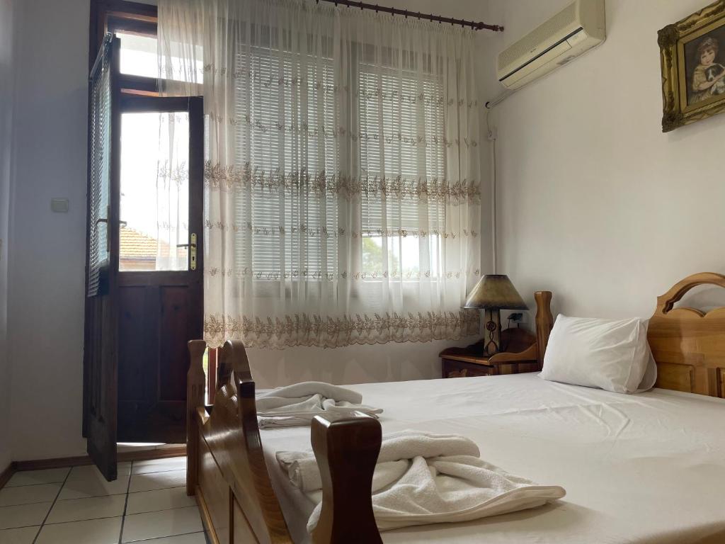1 dormitorio con 1 cama con sábanas blancas y ventana en Зелената къща en Hisarya