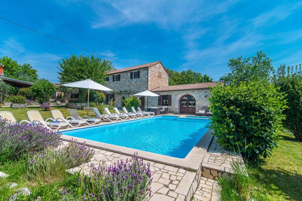 a swimming pool with chairs and a house at Villa Murva in Žminj