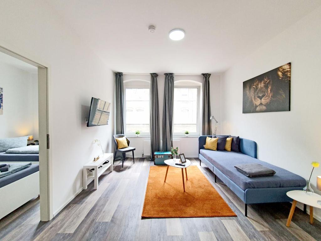 a living room with a blue couch and a bed at Apartments an der Kreuzstraße in Braunschweig