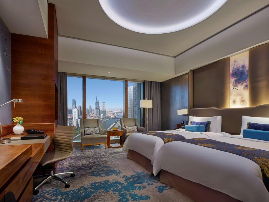a hotel room with two beds and a desk at Shangri-La Tianjin in Tianjin