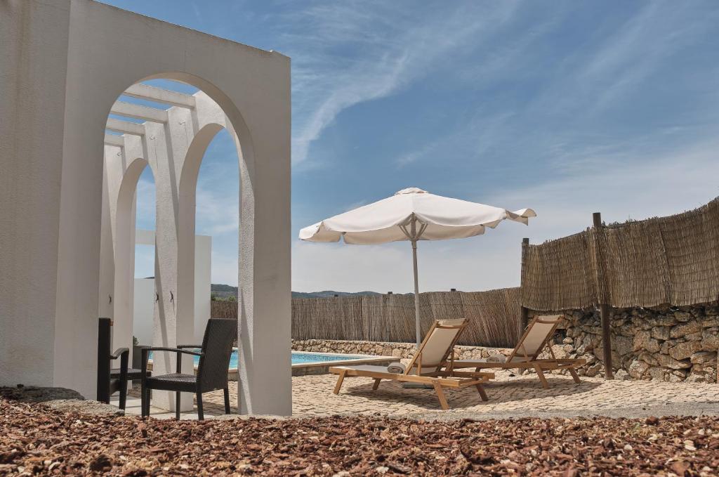 um pátio com cadeiras, um guarda-sol e uma piscina em Casa do Brasão em Marvão