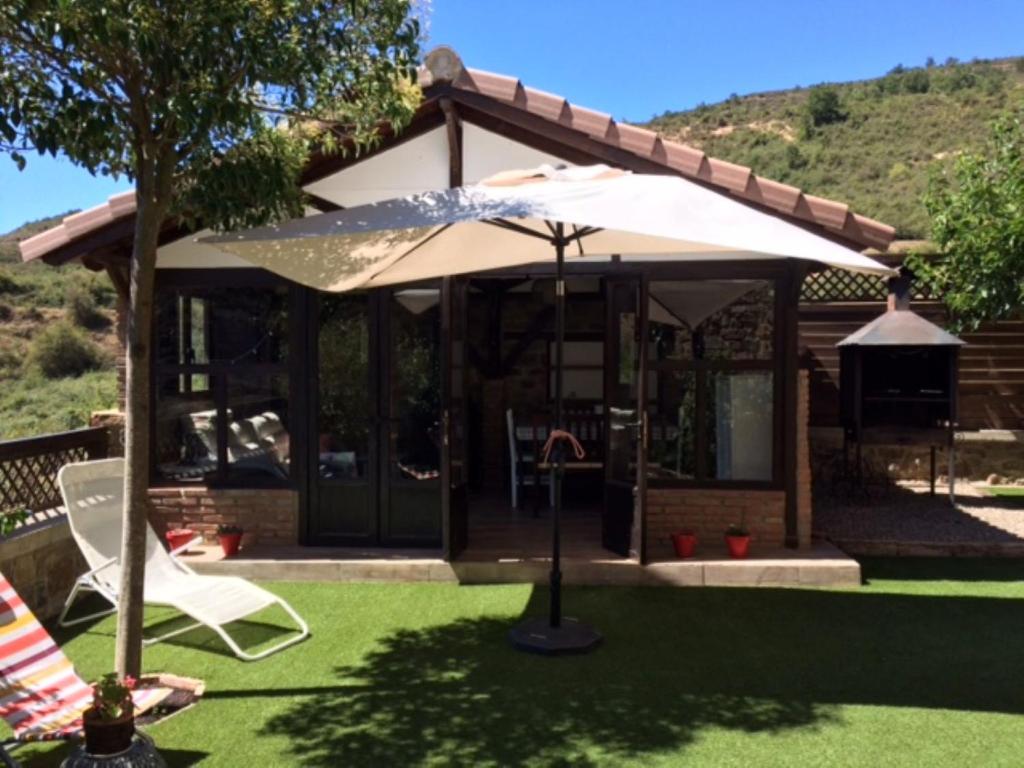 una casa con sombrilla y césped en Casa el EDEN de Cameros, en Laguna de Cameros