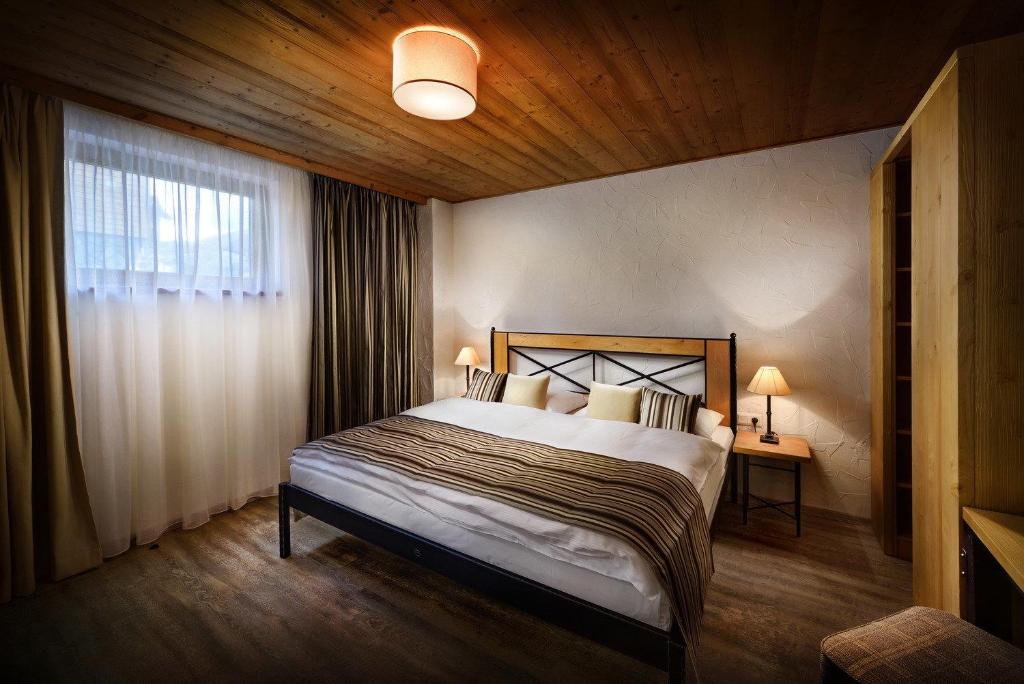 um quarto com uma cama grande num quarto com uma janela em Cardinal Jasna Mountain Wellness Apartment em Demanovska Dolina