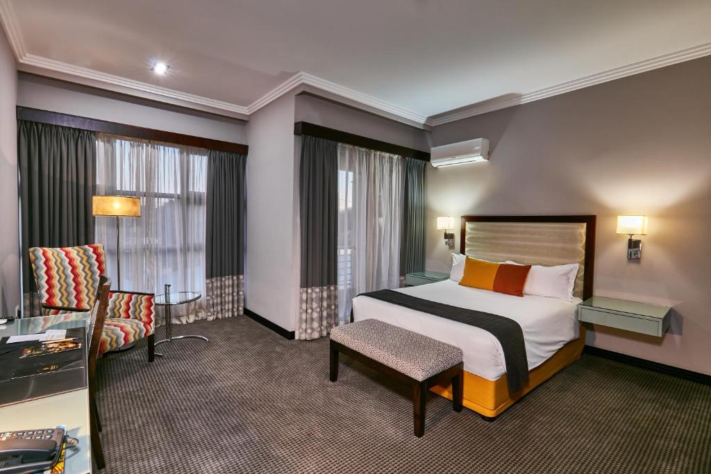 a hotel room with a bed and a chair at Regent Select Hotel in Gaborone