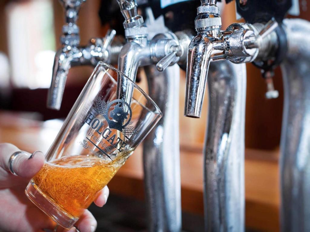 una persona sosteniendo un vaso de cerveza en un bar en Holgate Brewhouse, en Woodend