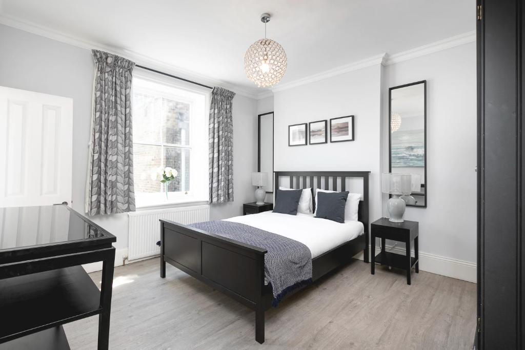 a white bedroom with a bed and a piano at PenthouseStays Notting Hill - Chic 2 Bedroom Apartment w/ King Beds - near Portobello Road & Kensington High Street in London