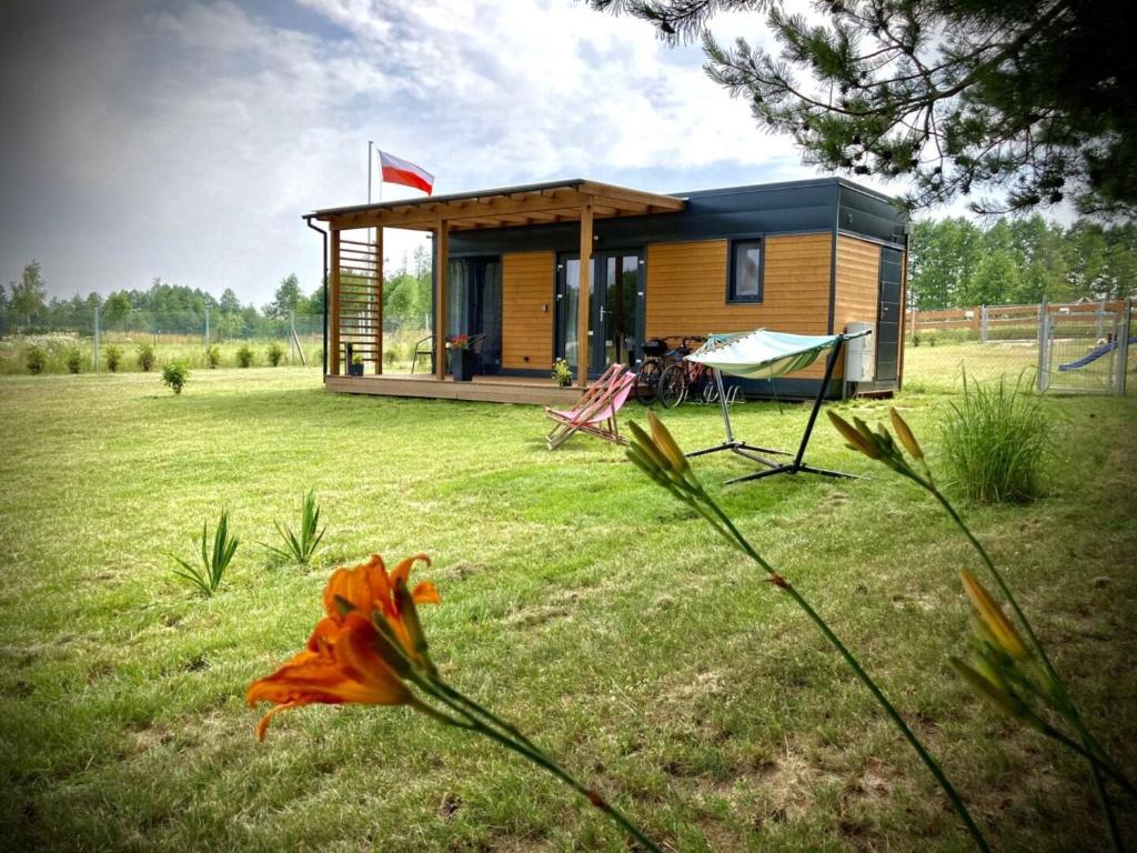una pequeña casa en un campo con una flor delante en Cisy Resort-idealny dla gości ze zwierzętami,ogrodzony teren na wyłączność,150 m od jeziora, en Ełk