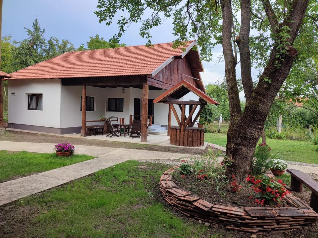 una pequeña casa blanca con techo rojo en Dumbrava Minunată, en Peşteana