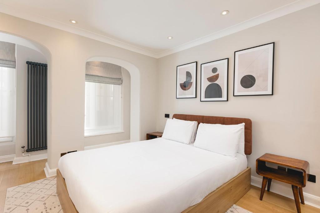 um quarto branco com uma cama grande e quadros na parede em PenthouseStays Chelsea - Luxury 2 Bedroom Apartment w/King Bed - near King's Road em Londres