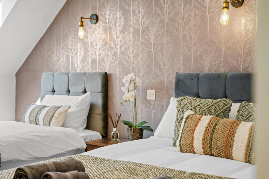 um quarto com 2 camas e papel de parede rosa em PRIME 3 BED HOUSE to BICESTER OUTLET for 8 People by Platinum Key Properties em Bicester