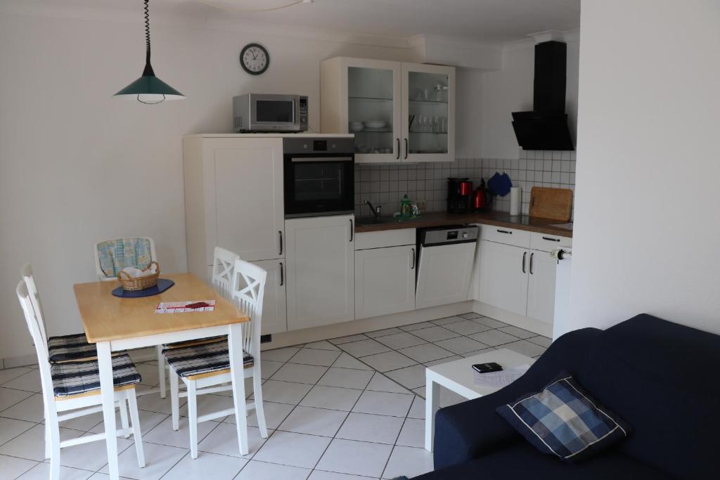 a kitchen with white cabinets and a table and chairs at Ferienwohnung 1066 App 3 in Tossens in Butjadingen OT Tossens