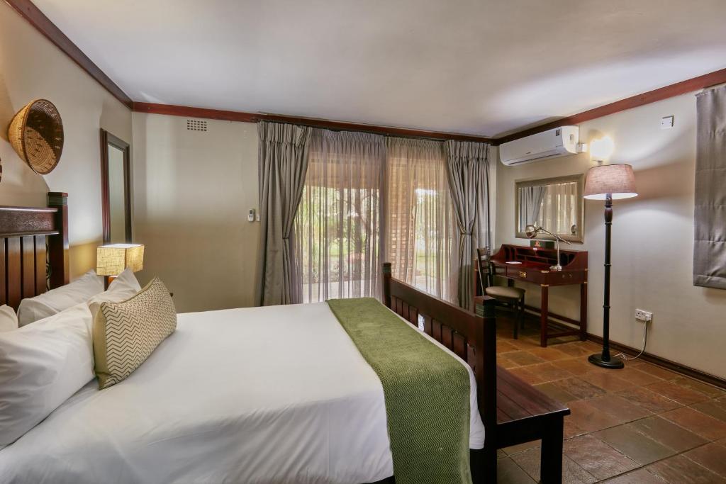 1 dormitorio con 1 cama grande y piano en Manong Game Lodge en Gaborone