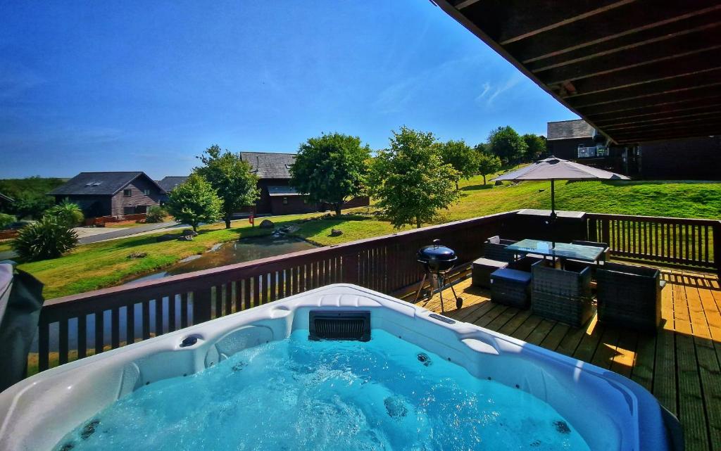 a hot tub on the deck of a house at Lake View Lodge in Saint Columb Major