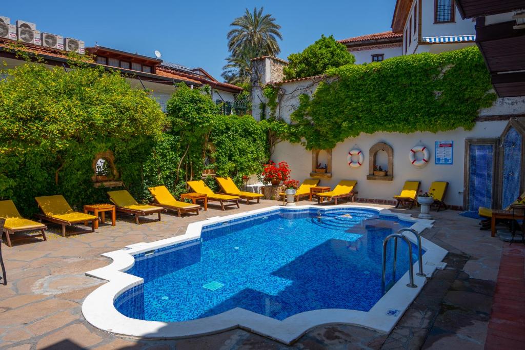 a swimming pool with yellow lounge chairs next to a house at Aspen Hotel Kaleiçi in Antalya