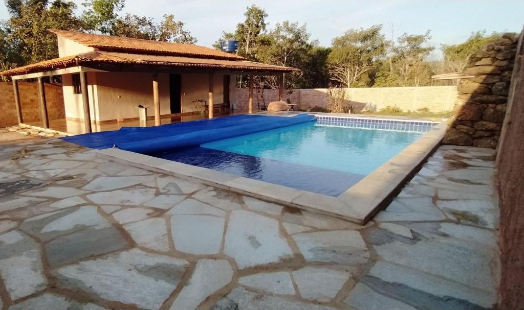 una piscina con patio in pietra e una casa di casa rural Bon Tempo a Pirenópolis