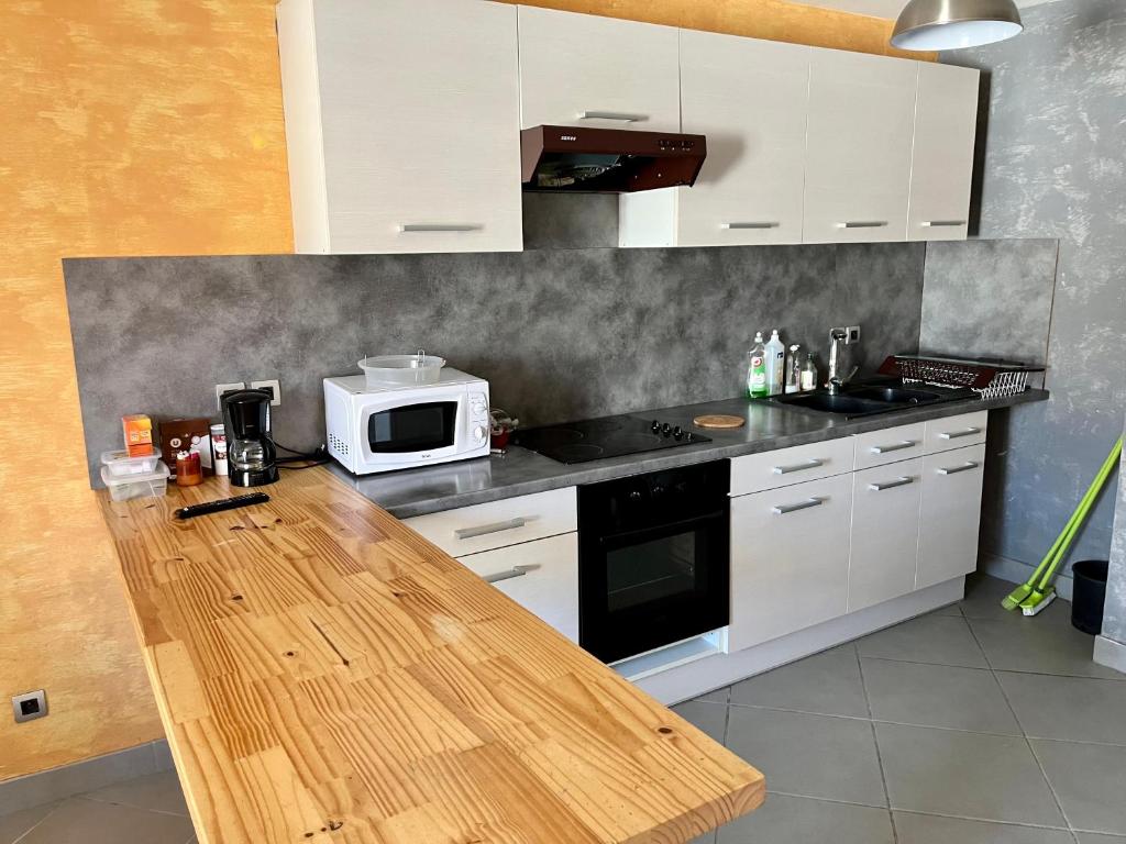 a kitchen with white cabinets and a counter with a microwave at Appartement 2 chambres - lits king size - wifi - baignoire in Le Puy en Velay