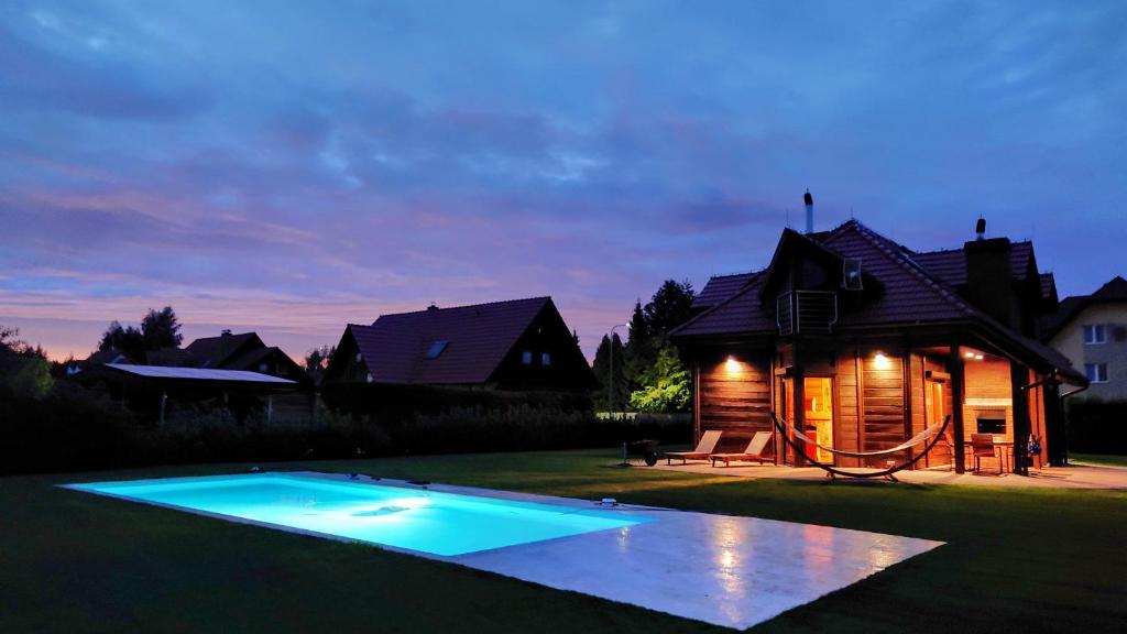a swimming pool in front of a house at night at Dom wakacyjny z basenem in Dębki