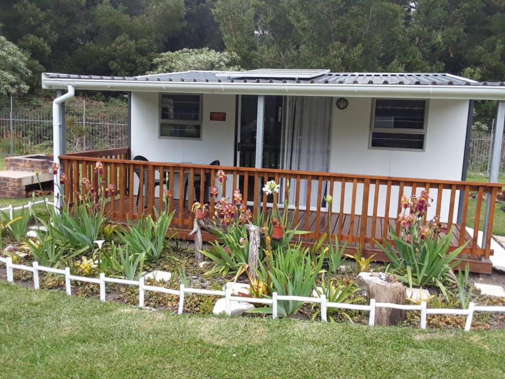 a house with a deck with flowers in the yard at Nadine's Self - Catering Accommodation in Stormsrivier