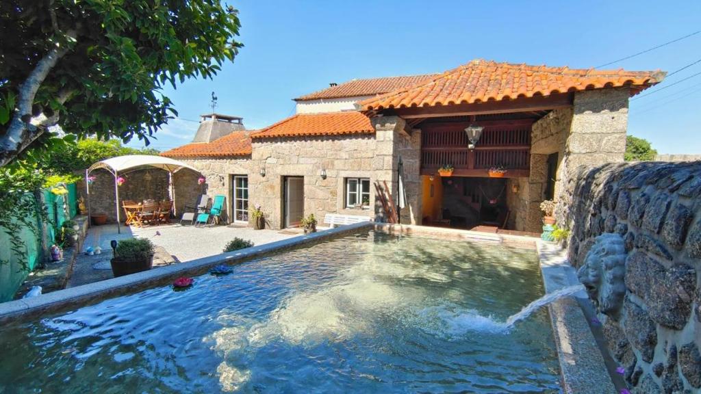 a house with a swimming pool in front of a house at Casa Rústica com Piscina Privada - Perto do Porto in Landim