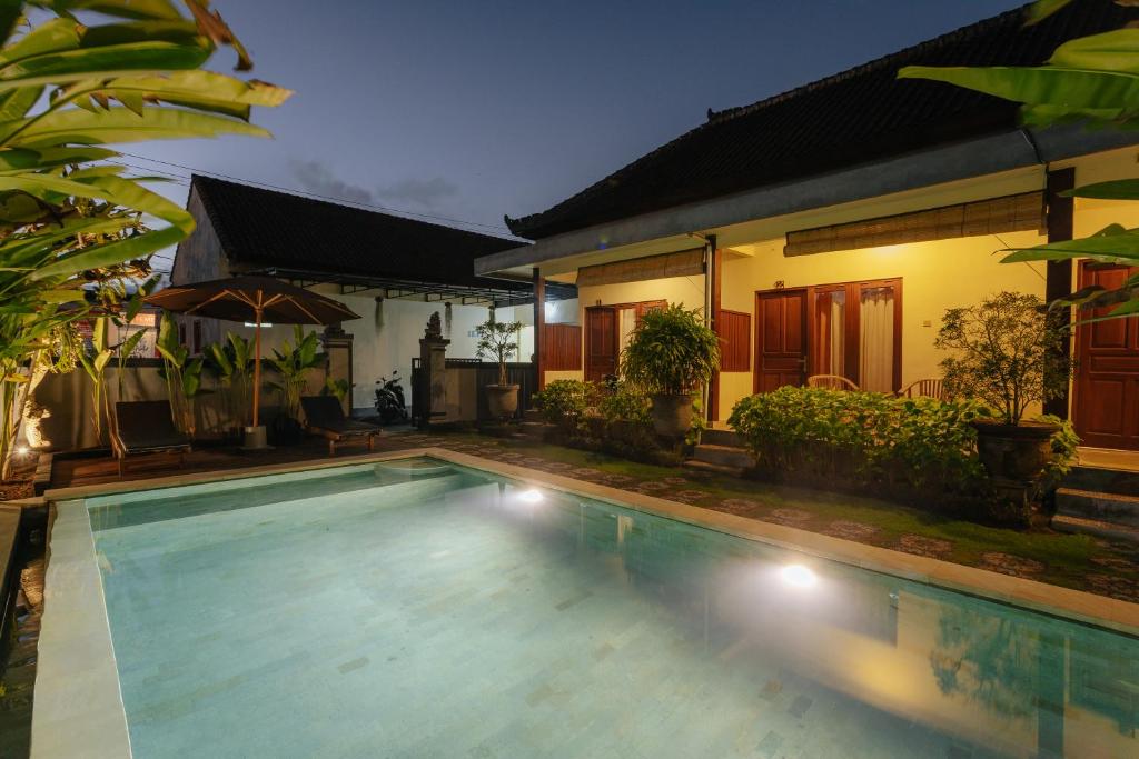 a swimming pool in front of a house at BUBU CANGGU Guesthouse in Canggu