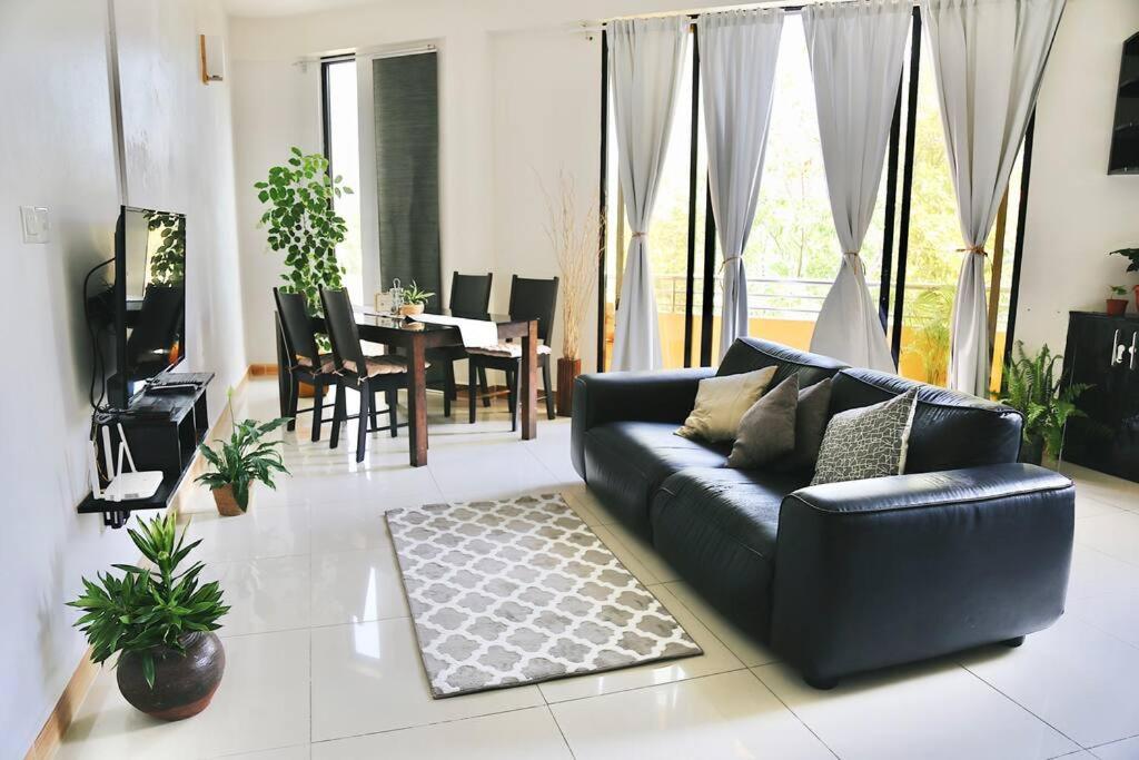 sala de estar con sofá negro y mesa en BODU ASHI MALDIVES - Central 3 Bedroom Apartment, en Hulhumale