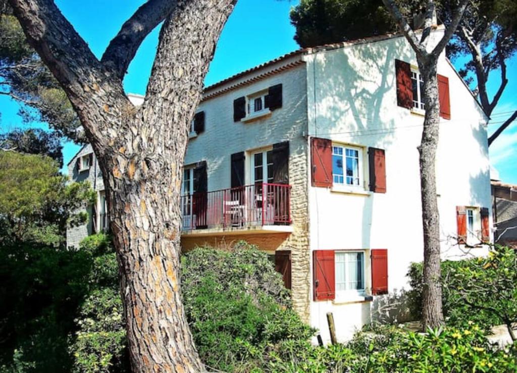 une maison blanche avec des portes rouges et un arbre dans l'établissement Villa Nausicaa, à Hyères