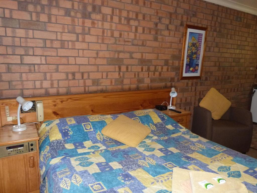 a bedroom with a bed and a brick wall at Wintersun Motel in Victor Harbor