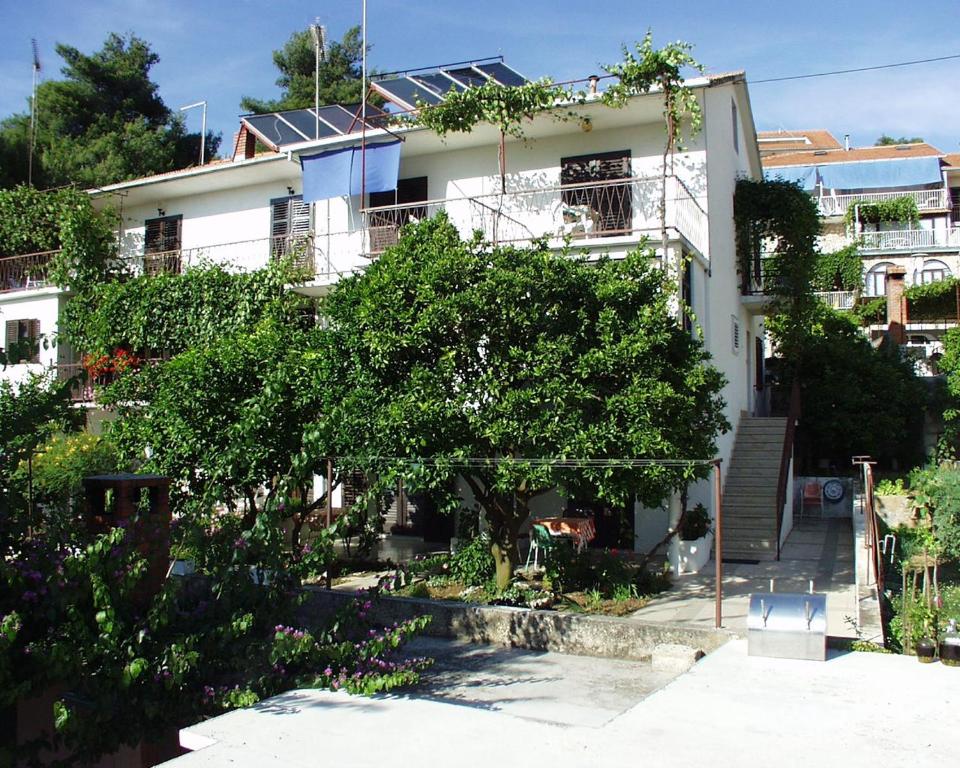 a white building with a tree in front of it at Rooms by the sea Jelsa, Hvar - 127 in Jelsa