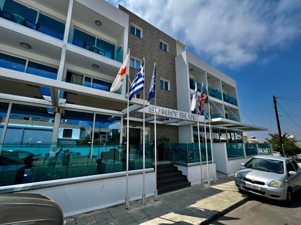 a car parked in front of a building with flags at Sunny Blue Hotel in Ayia Napa