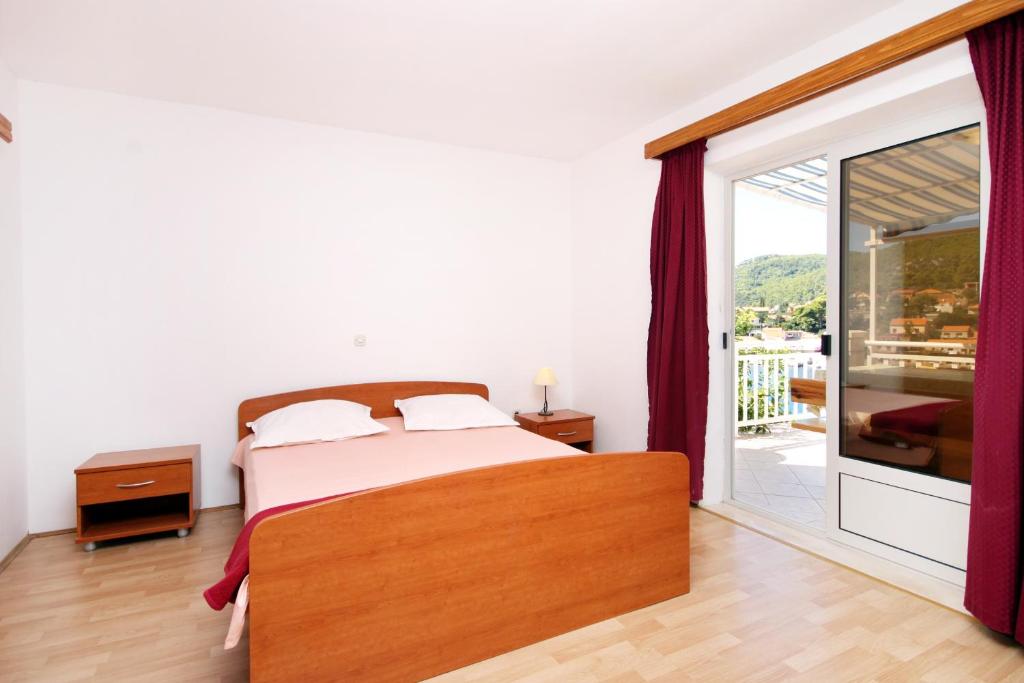 a bedroom with a bed and a sliding glass door at Apartments by the sea Brna, Korcula - 147 in Smokvica