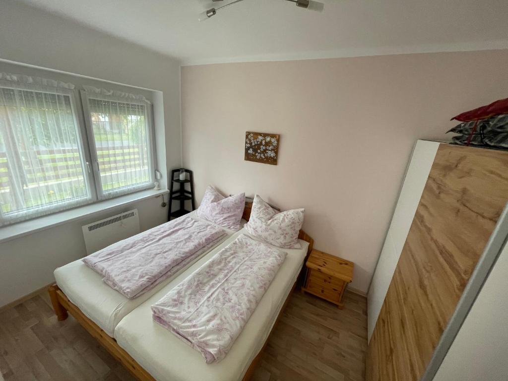 a small bedroom with a bed and two windows at Két szobás, teraszos, kertes vendégház in Balatonmáriafürdő