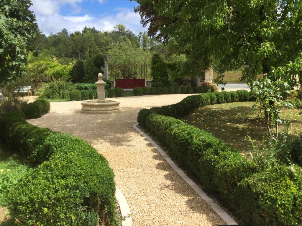 un jardín con una estatua en medio de un camino en chambres d'hôtes à la claire fontaine en Sorges