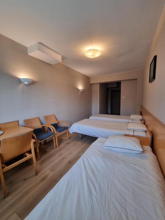 um quarto de hospital com três camas e cadeiras em Biłgoraj Aparthotel em Bilgoraj