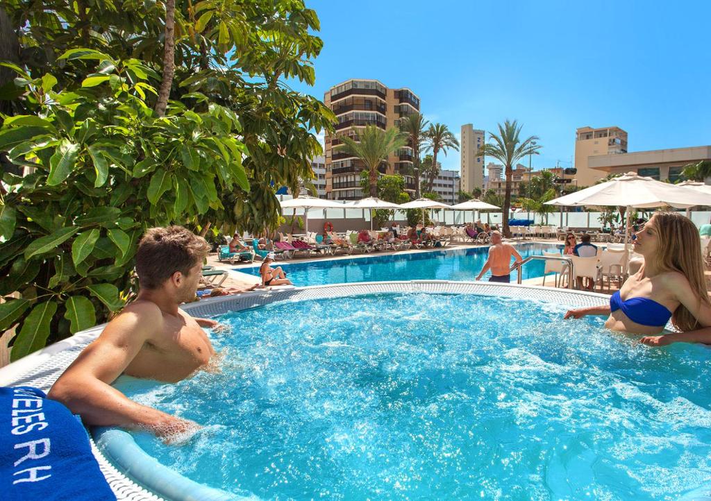 a man and a woman sitting in a swimming pool at Hotel RH Royal - Adults Only in Benidorm