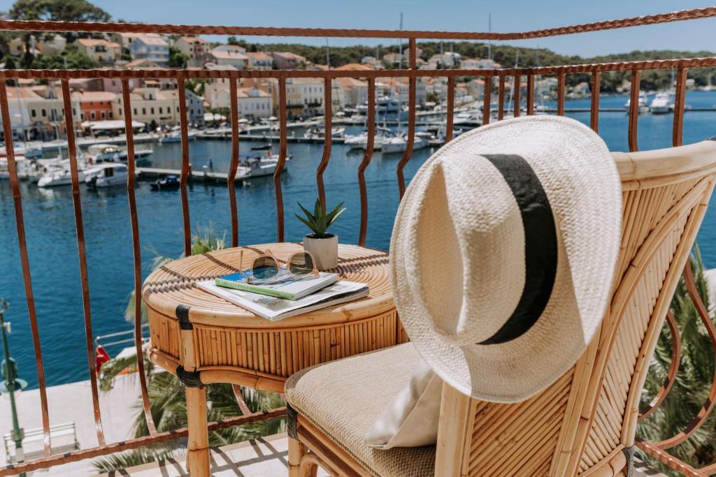 a hat sitting on a table on a balcony with a marina at Hotel Apoksiomen in Mali Lošinj