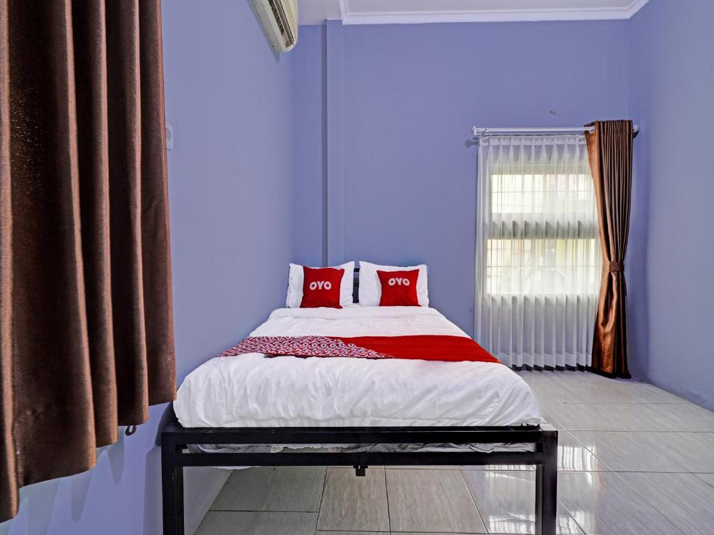 Un dormitorio con una cama con almohadas rojas y una ventana en OYO Life 91592 Aaliya Guest House Syariah, en Lebakwangi