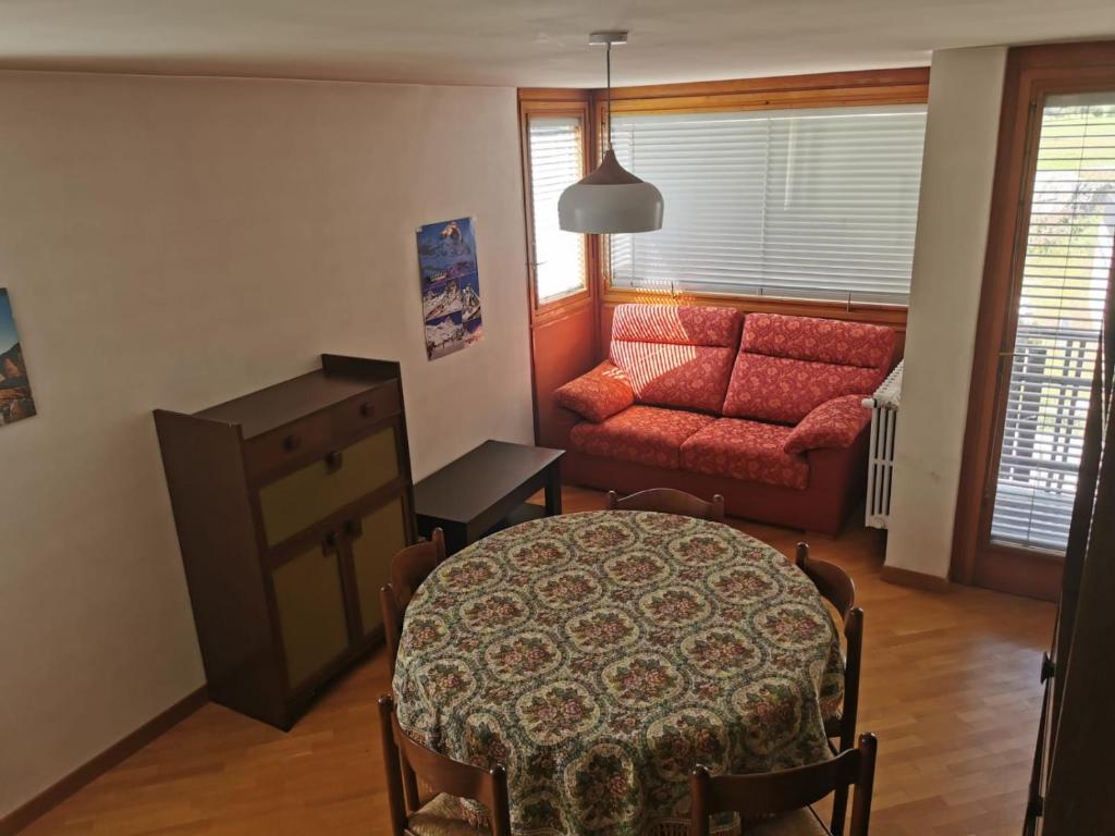 a living room with a table and a red couch at Homey Apartment in the heart of Cervinia in Breuil-Cervinia